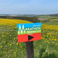 Wegschild zum Wandermarathon vor einer Wiese