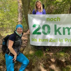 Frauen neben schild, dass anzeigt, dass es noch 20 km bis zum Ziel sind