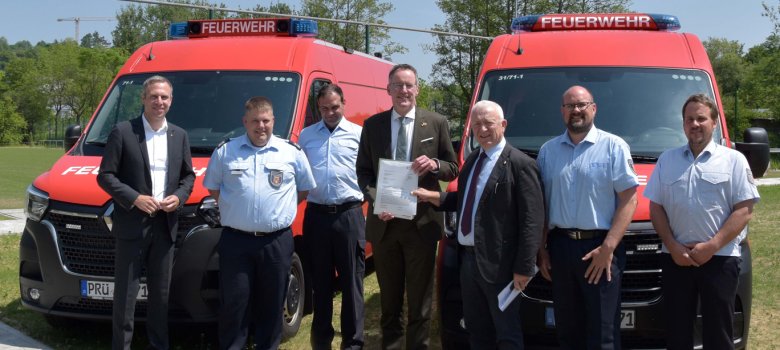 Teilnehmer vor Feuerwehrauto bei Übergabe des Förderbescheide