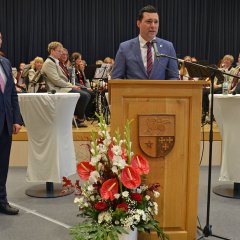 Der neue Bürgermeister Dr. Reuschen hält am Rednerpult eine Ansprache zur Verabschiedung von Bürgermeister Söhngen, der daneben steht.