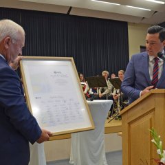 Dr. Reuschen überreicht Bürgermeister Söhngen ein herzliches Dankeschön in einem Bilderrahmen mit zahlreichen Unterschriften.