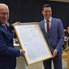 Dr. Reuschen überreicht Bürgermeister Söhngen ein herzliches Dankeschön in einem Bilderrahmen mit zahlreichen Unterschriften.