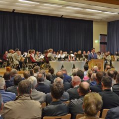 Bürgermeister Dr. Reuschen spricht am Rednerpult vor den Gästen, während hinter ihm der „Projekt-Musikverein“ sitzt.