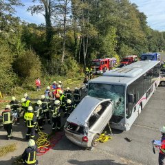 Simulierter Verkehrsunfall wo ein Auto in einen Bus gefahren ist. Rund um die simulierte Unfallstelle sieht man Helfer bei der Bergung.