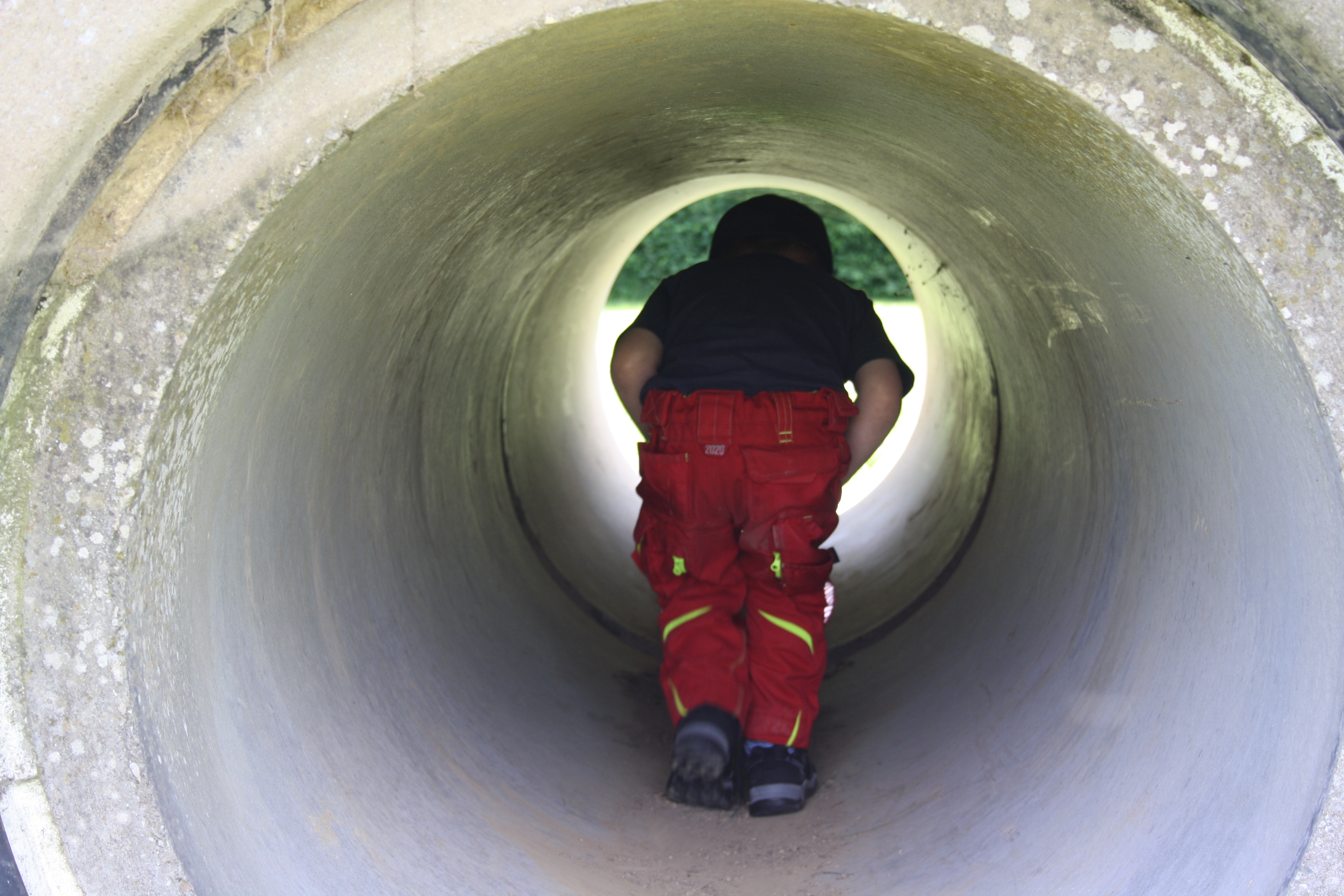 Kind auf Spielplatz beim Durchlaufen einer Betonröhre